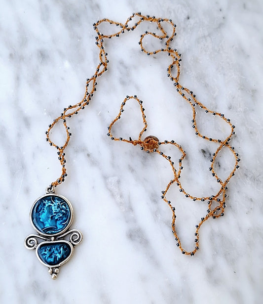 Long crochet necklace with turquoise enameled pewter pendant.